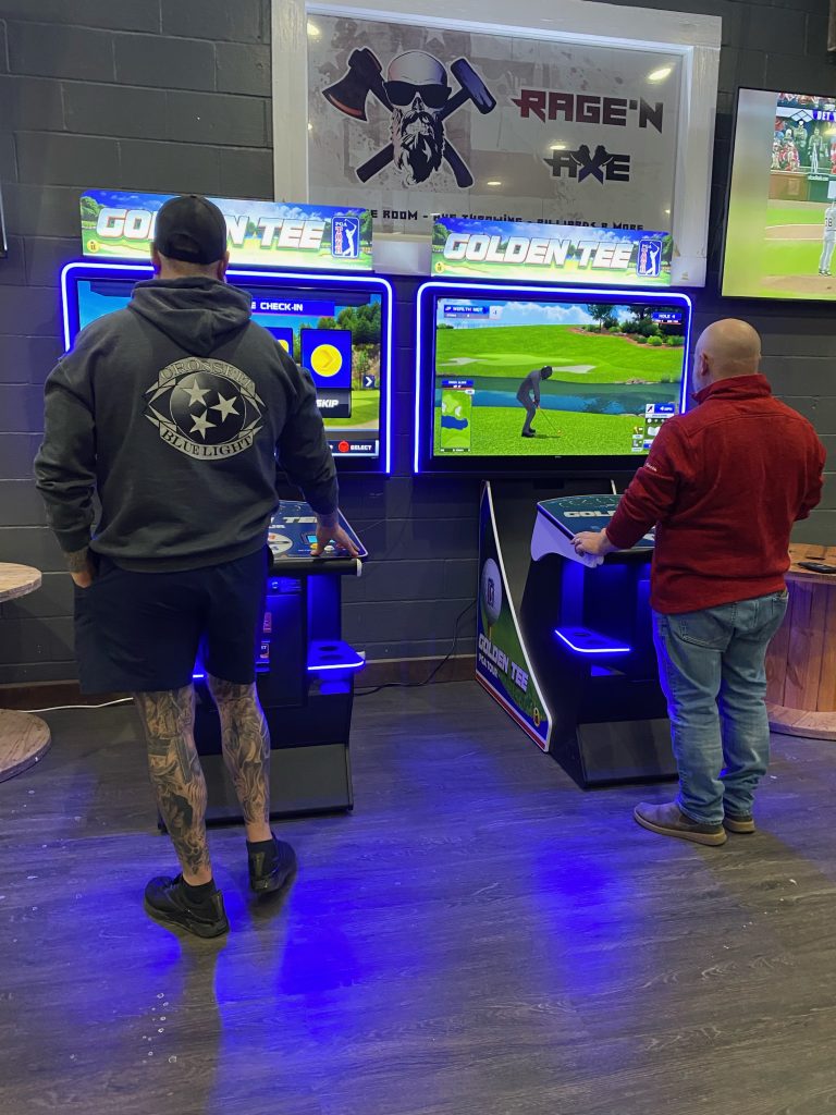 Guests playing Golden Tee golf arcade games at Rage’N Axe Guests playing Golden Tee golf arcade games at Rage’N Axe